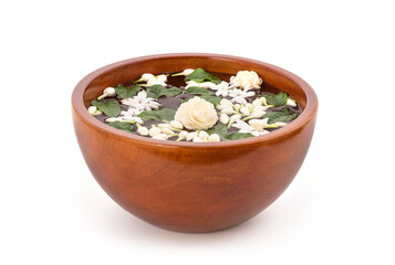 Floating jasmine flowers and green leaves in the water on wooden bowl isolated on white background.