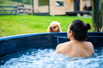 Young woman in an open-air bath with a view of the mountains. Young woman with her dog.