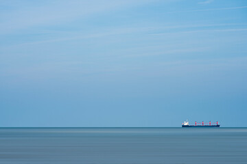Container ship sailing at sea with a blue sky as background