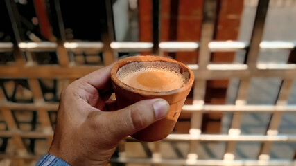 Hands holding a clay cup of tea in morning