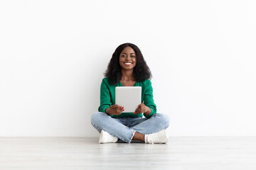 Fototapeta na wymiar Smiling black woman using digital tablet, white background