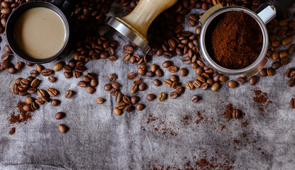 Fresh roasted coffee background. Banner. Tamper and portafilter on a gray linen background.