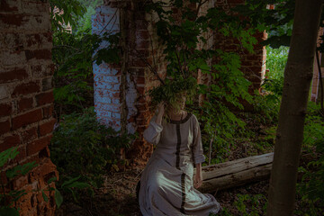 Young woman in pagan wreath with horns in ruins