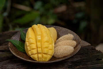 Face mask with ripe mango fruits for skin treatment and on an old wood background.