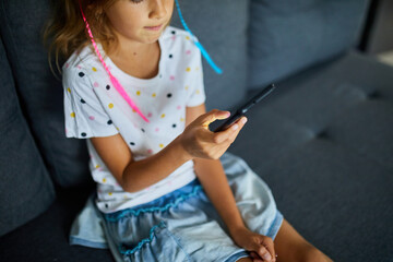 Child using cellphone on the sofa in modern and bright apartment