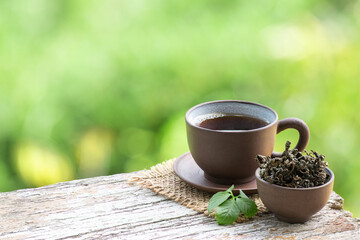 Fresh and dried gynostemma pentaphyllum or jiaogulan leaves and tea on bokeh nature background.