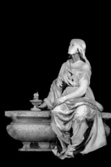 Sad and desperate woman on tomb as a symbol of death and the end of human life. An ancient statue isolated on black background.