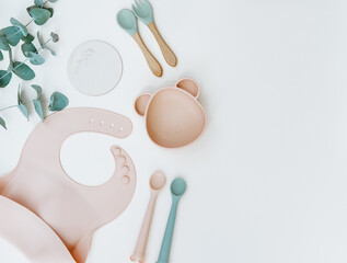 Baby feeding accessories. Silicone bib, Baby set dishes. Flat lay, top view, copy space.