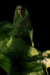 Girl posing in green draping on dark background