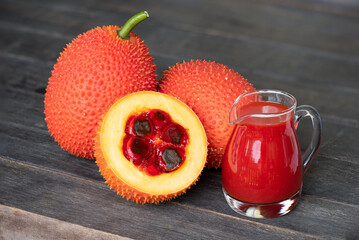 Gac fruits and juice on an old wooden background.