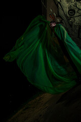 Girl posing in green draping on dark background