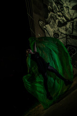 Girl posing in green draping on dark background