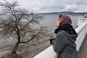 Portrait of a young woman standing on Black Sea embankment on winter day. Gelendzhik, Krasnodar...