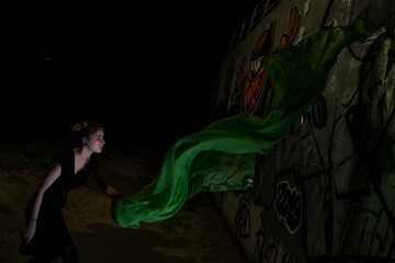 Girl posing in green draping on dark background
