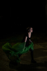 Girl posing in green draping on dark background