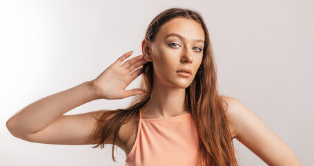 Beautiful young girl holds his hand near his ear, wants to hear better on a white background with a place for advertising mockup