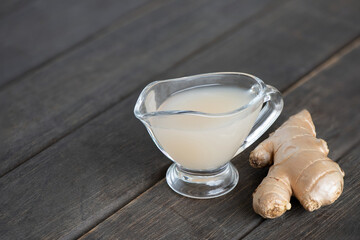Ginger rhizome and juice on an old wood background.