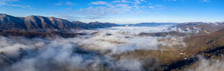 Panoramic view of covered with fog valley on sunny winter day. Surroundings of Gelendzhik, Krasnodar Krai, Russia.