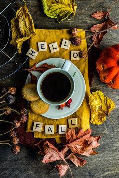 Cup of coffee on a table with autumn leaves, decoration and the words Hello Fall