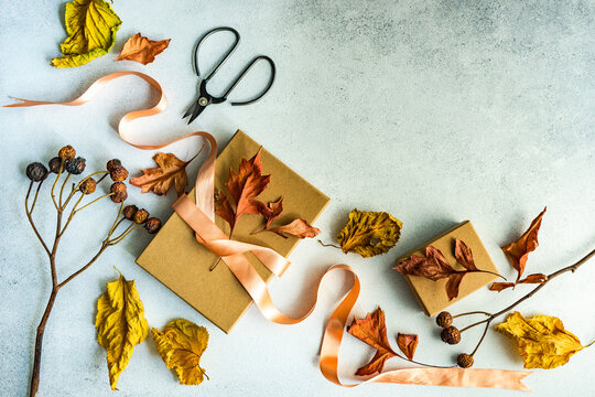 Autumnal gift box tied with a ribbon and dried autumn leaf decorations on a table