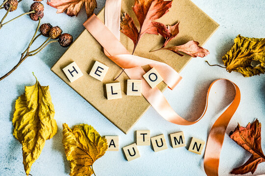 Autumnal gift box tied with a ribbon, dried autumn leaf decoration and words hello autumn