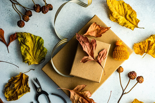 Two autumnal gift boxes tied with a ribbon, dried autumn leaf and berry decorations