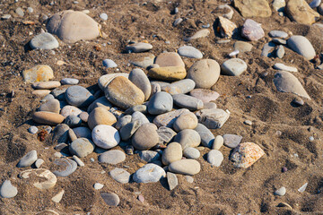 Colored round stones on the sand on the Black Sea coast in Crimea