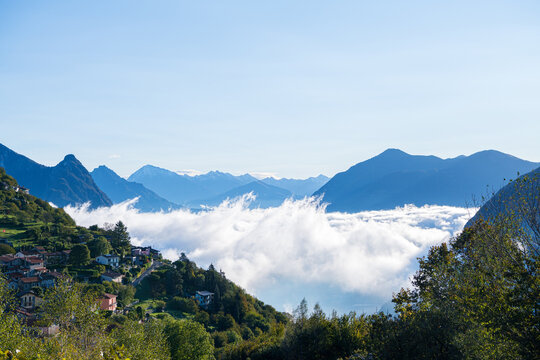 Bre village and mountain peaks through a cloud carpet in Alps, Lake Lugano, Switzerland