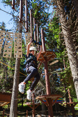 Little girl in safety equipment at adventure amusement park. Child having fun outdoor