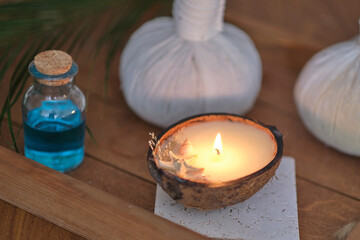 candle with the scent of coconut on a wooden table. Beautiful tropical spa concept. Cotton pouches...