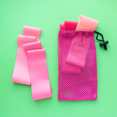 Set of fitness rubber bands in bag on green background, top view