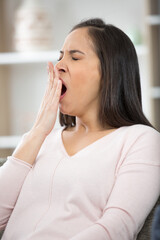 young bored woman yawning at home