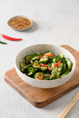 Asian spicy salad Broken Cucumbers with fresh coriander, ginger on white background. Popular Chinese cold appetizer. Close up. Vertical format. Copy space.