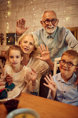 Happy grandparents with grandkids celebrate Thanksgiving and waving to camera.
