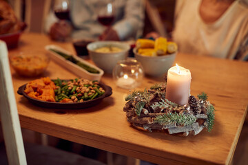 Close-up of Thanksgiving decoration on dining table with people in the background.