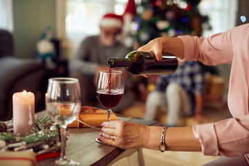 Close-up of woman pours wine while celebrating Christmas at home.