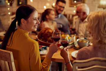 Happy women toast with wine during Thanksgiving dinner with their family.