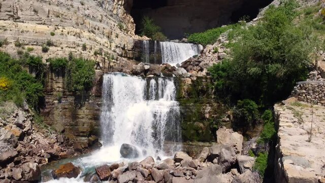 Tourist Walking By Rocky Path Overlooking Afqa Waterfall In Lebanon - aerial shot