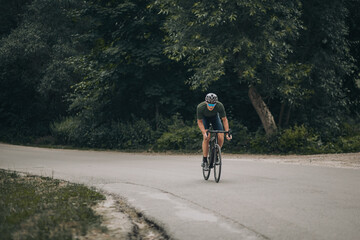 Active man riding in sportswear bike along forest trail
