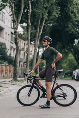 Professional cyclist resting on bike after ride on city street