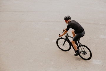 Active man in sport outfit riding black bike outdoors