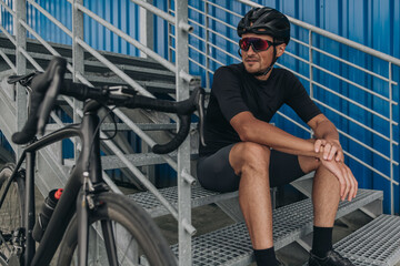 Cyclist looking at his bike while sitting on metal stairs