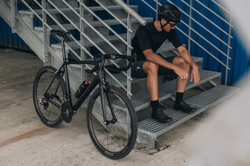Fototapeta na wymiar Man resting on metal stairs after active cycling