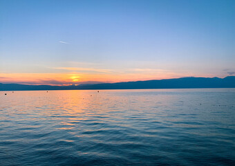 Beautiful sunset on the lake, natural colors, silhouette of the mountains background, deep blue color