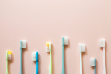 Colorful toothbrushes on pink background. top view, copy space