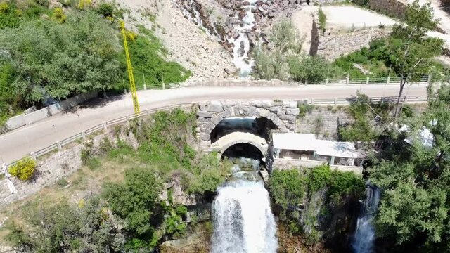 Old Bridge And Afqa Waterfall Which Water Flows Into Abraham Bridge In Afqa, Lebanon. drone tilt-up