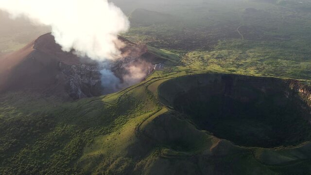 Cinemaic Aerial shot over 2 volcano craters. Active volcanno full of steam and inactive covered with vegetation  . Erupting Volcano in Central America. Masaya, the &ldquo;Mouth of Hell&rdquo;, Nicaragua.