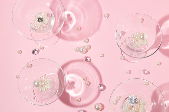 Christmas party creative layout with white pearls, diamonds and margarita and martini cocktail glasses on  pastel pink background. Retro fashion aesthetic party concept. Trendy New Year idea