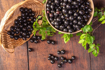 Jabuticaba, Jabuticabas freshly harvested in pots and baskets arranged on rustic wood, top view.
