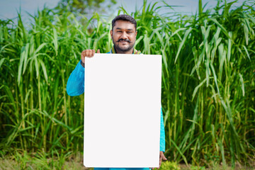 Indian farmer showing white board in agricultural field